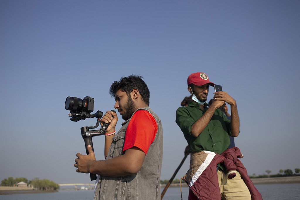 Local film fixer assisting camera crew during an outdoor shoot in Bangladesh