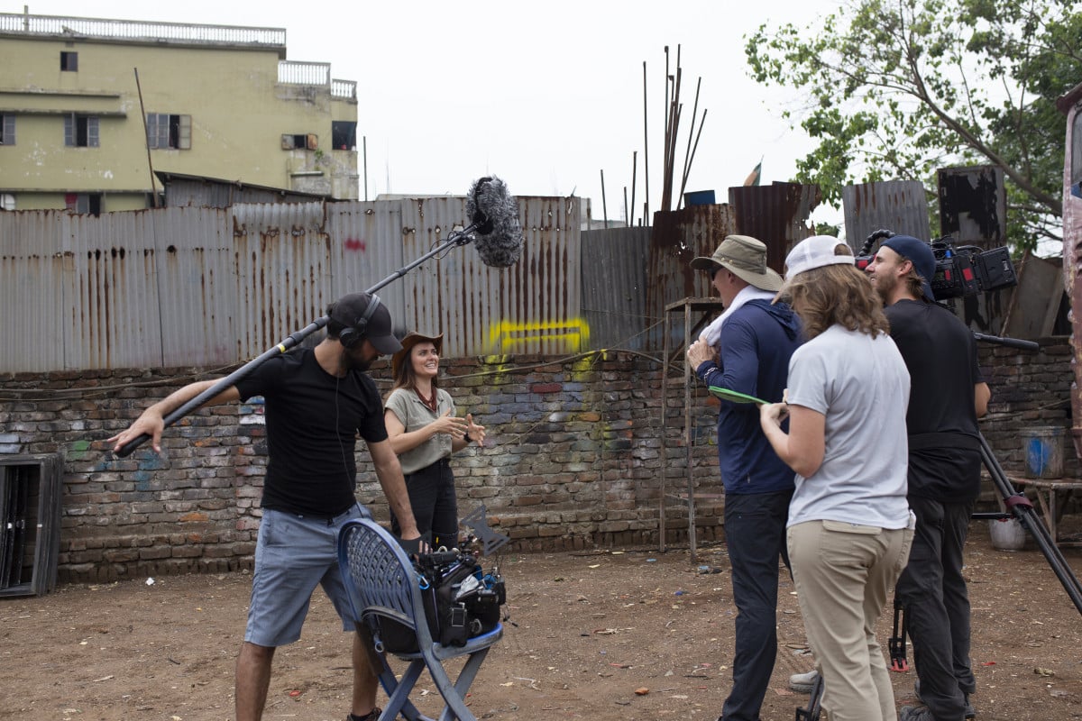 local production Coordinator reviewing documents and interview setup with foreign filming crew as part of on-ground media support in Bangladesh