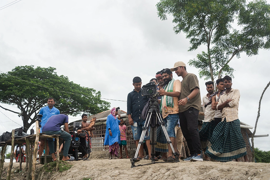 A professional film crew with a cinema camera filming in a vibrant, coastal town in Sundarbans, Bangladesh.