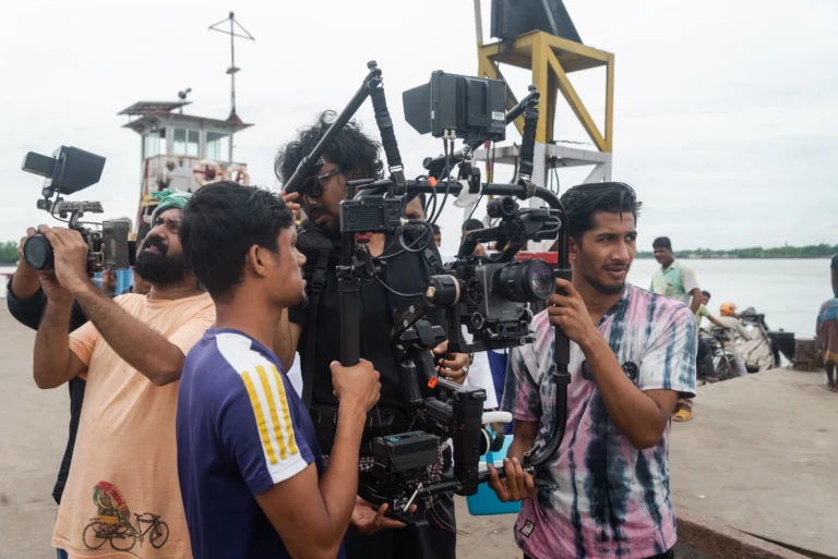 Bangladeshi documentary cinematographer operating a cinema camera on a remote-directed shoot in coastal Bangladesh